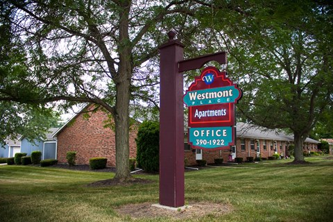 A sign for Westmont Apartments stands in front of a building.