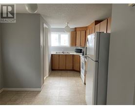 A kitchen with a refrigerator, sink, and cabinets.