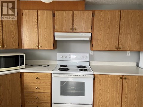 A kitchen with wooden cabinets and a white stove top oven.