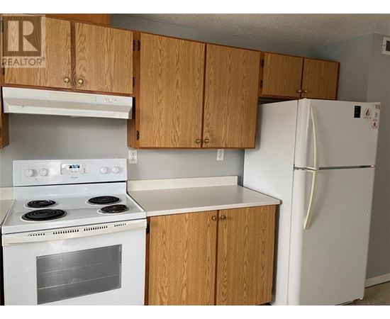 A kitchen with a white stove and refrigerator.