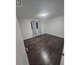 A room with wooden flooring and a window with curtains.