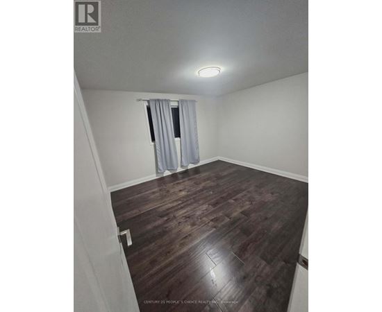 A room with wooden flooring and a window with curtains.