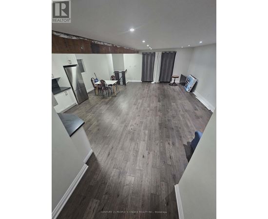 A realtor photo of a room with wood flooring and a kitchenette.