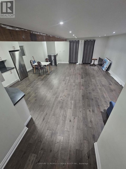 A realtor photo of a room with wood flooring and a kitchenette.