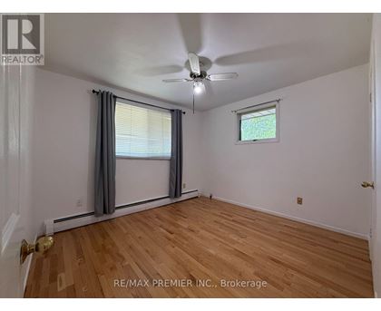 A room with a ceiling fan and a window with a view of trees.