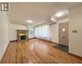 A spacious room with a fireplace and wooden flooring.