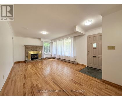 A spacious room with a fireplace and wooden flooring.