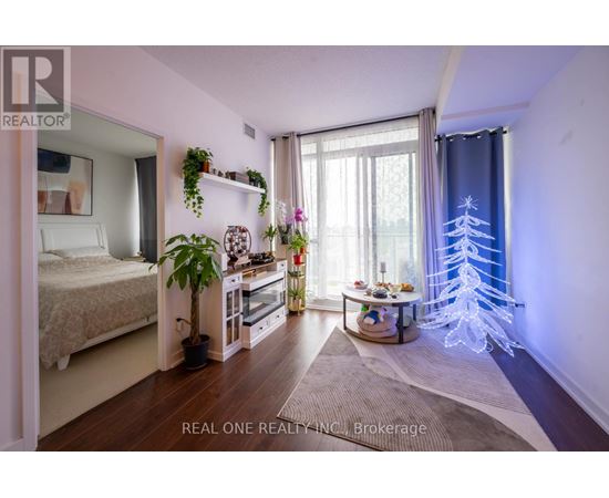 A bedroom with a bed, a table with a plant, and a window with a blue curtain.