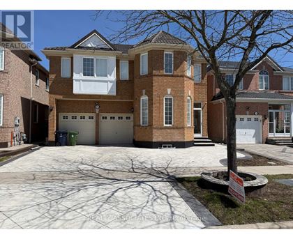 A large brick house with a tree in front and a sign that says REALTOR.