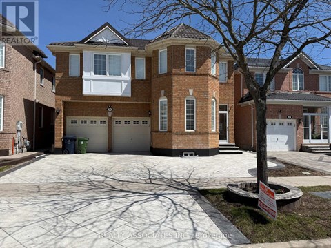 A large brick house with a tree in front and a sign that says REALTOR.