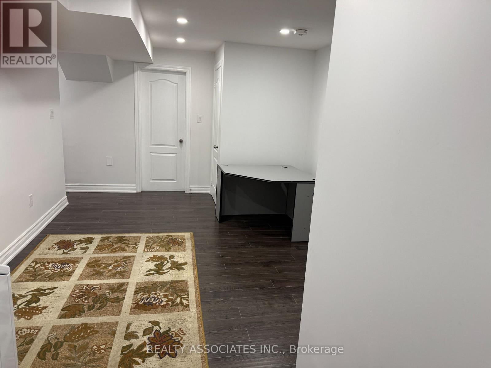 A room with a rug on the floor and a door in the background.