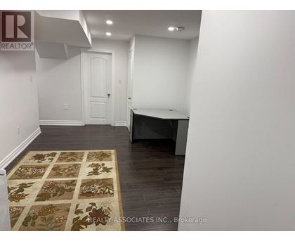 A room with a rug on the floor and a door in the background.