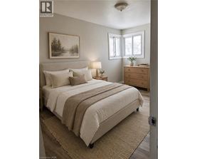 A bedroom with a large bed, a nightstand with a lamp, and a painting on the wall.