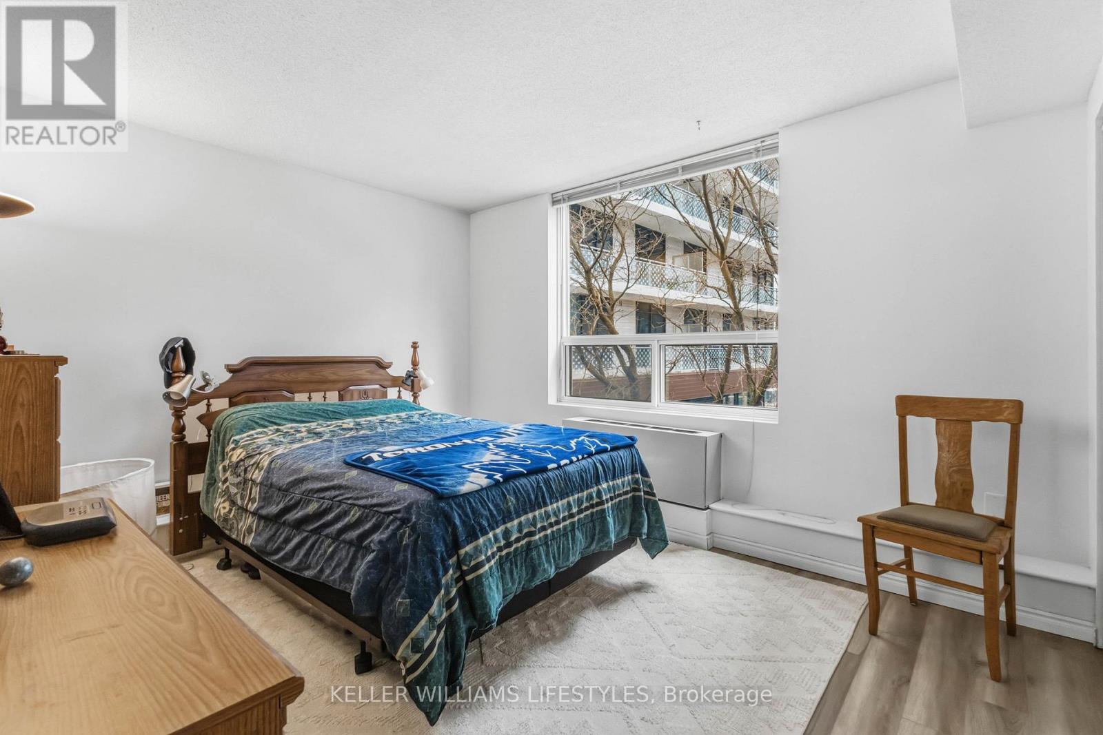 A bedroom with a bed, chair, and window.