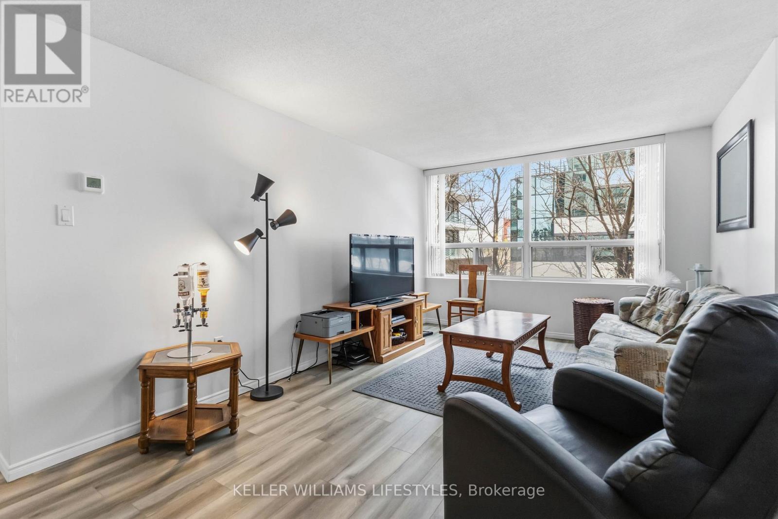 A living room with a grey couch and wooden side tables.