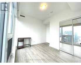 A spacious room with a wooden floor and a large window overlooking the city.