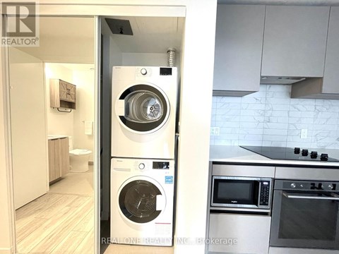 A modern kitchen with a washer and dryer built into the cabinetry.
