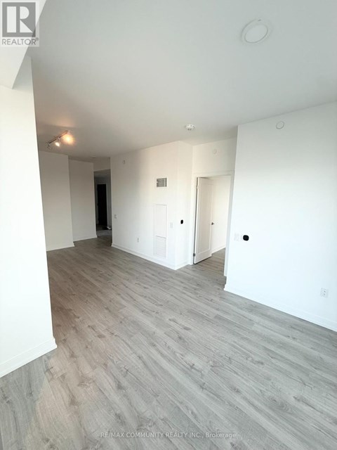 A spacious room with wood flooring and white walls.