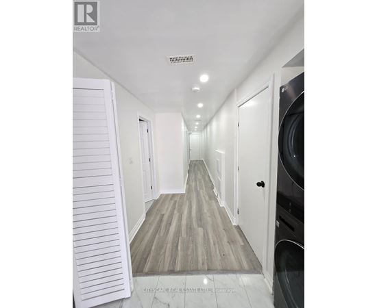 A long hallway with white doors and a wooden floor.