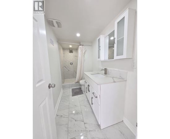 A white bathroom with a marble floor and a walk-in shower.