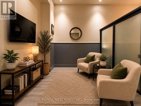 A living room with a flat screen TV mounted on the wall and two armchairs with green cushions.