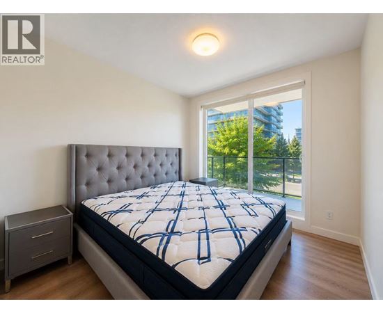 A bedroom with a large bed and a window overlooking a balcony.