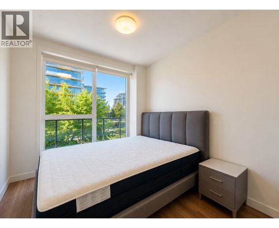 A bedroom with a bed, nightstand, and window overlooking a balcony.