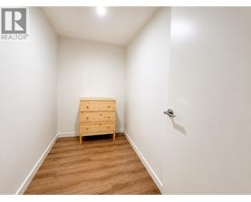 A bedroom with a wooden chest of drawers and a white wall.