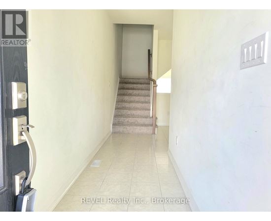 A hallway with a staircase leading to a door.