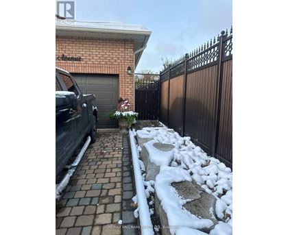 A black truck is parked in front of a house with a sign that says "RE/MAX Hallmark Realty, Brockton.".