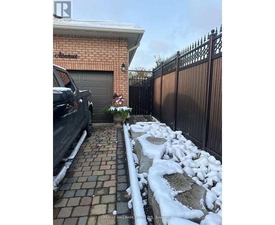 A black truck is parked in front of a house with a sign that says "RE/MAX Hallmark Realty, Brockton.".