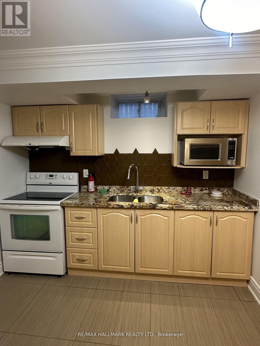 A kitchen with a white oven and microwave, a sink, and wooden cabinets.