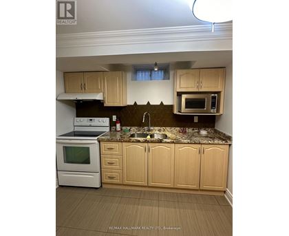 A kitchen with a white oven and microwave, a sink, and wooden cabinets.