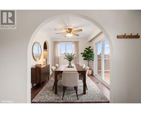 A dining room with a round mirror and a ceiling fan.