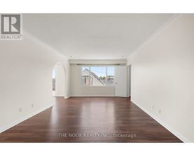 A spacious room with wooden flooring and white walls.