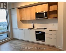 A kitchen with white cabinets and a black microwave above the stove.