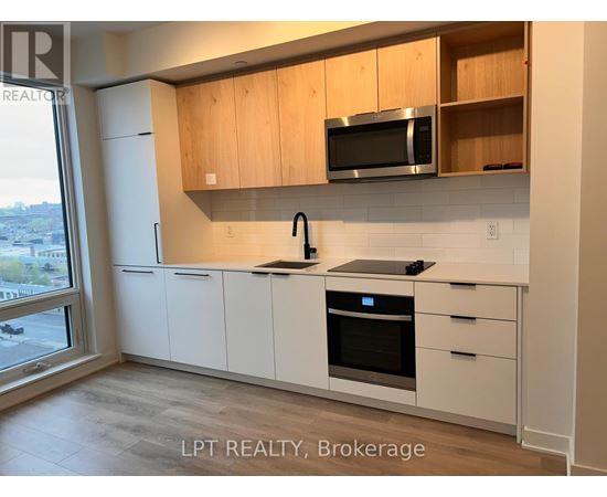A kitchen with white cabinets and a black microwave above the stove.