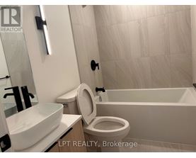 A white toilet with a white sink and a white bathtub in a bathroom.