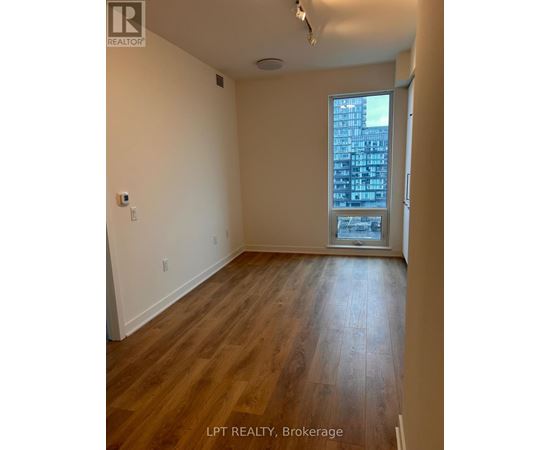 A room with wooden flooring and a window overlooking a cityscape.
