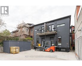 A forklift is parked in front of a grey building.