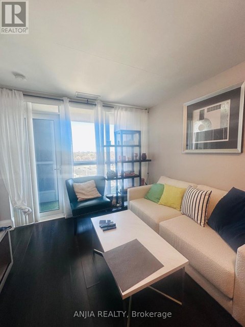 A living room with a couch, coffee table, and a window with curtains.