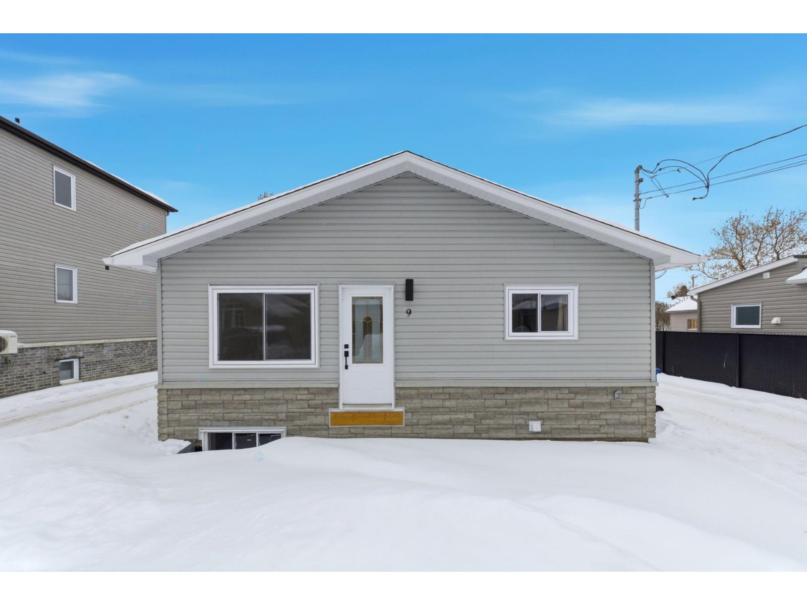 A small house with a white door and windows is surrounded by snow.