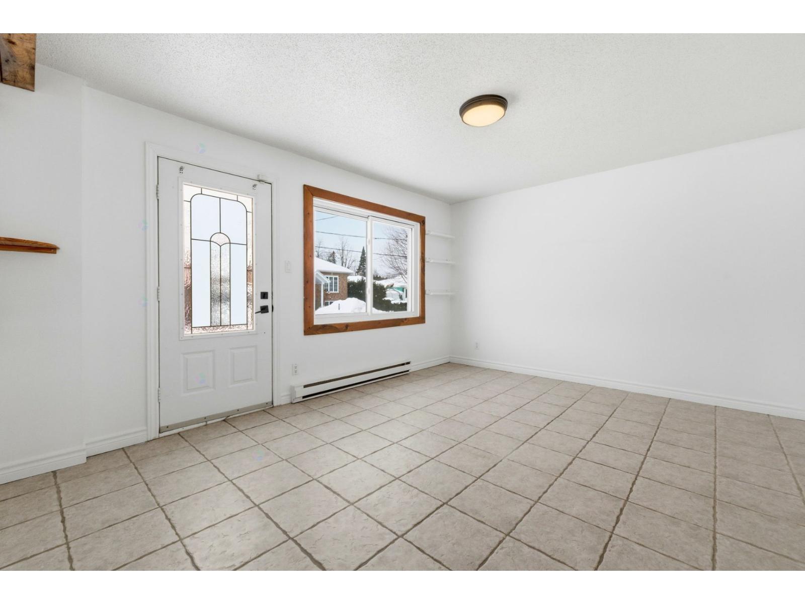 A room with a white door and a window with a view of a house.