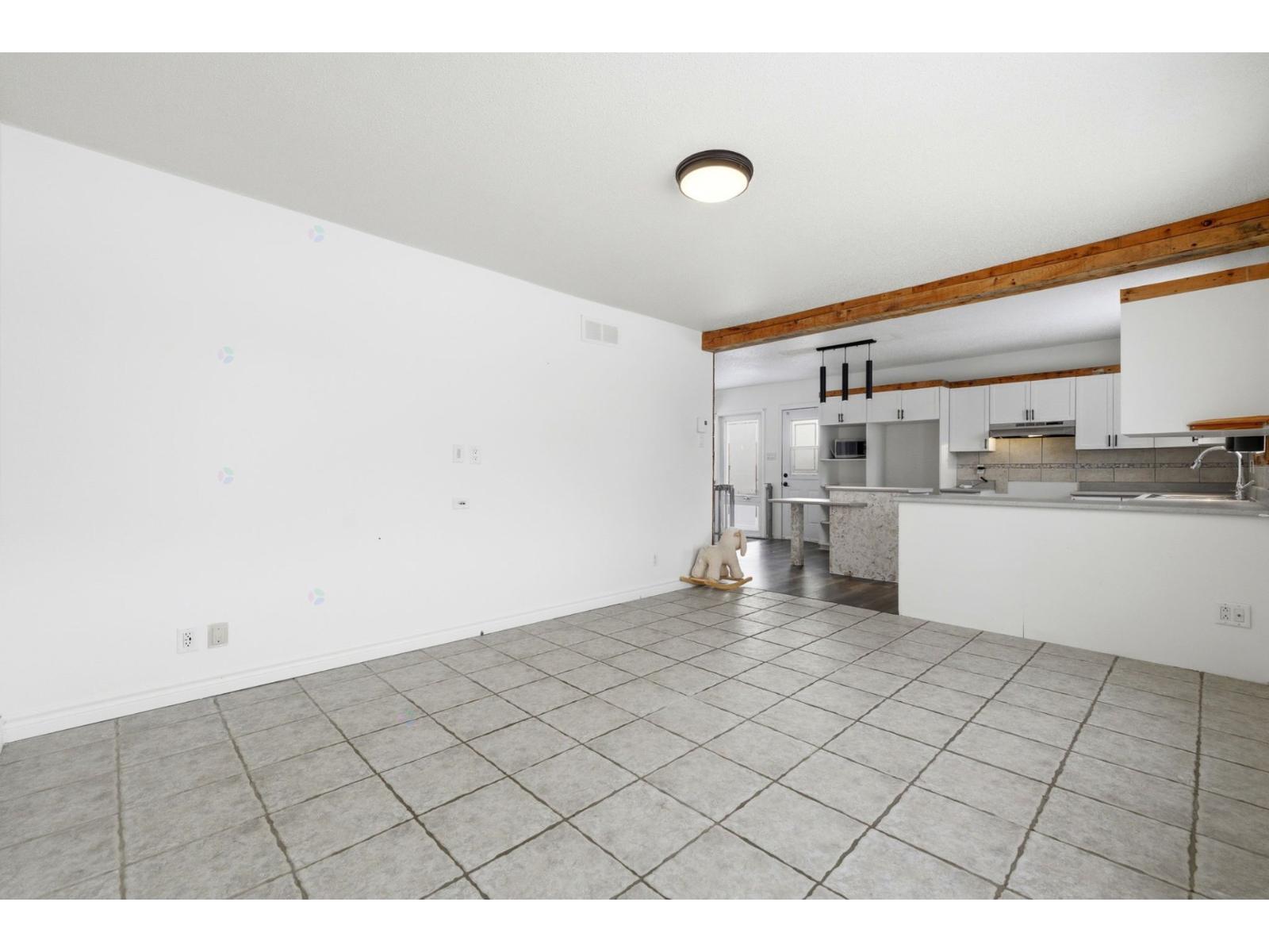A large empty room with a kitchen in the background.