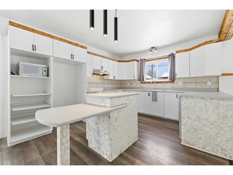 A kitchen with white cabinets and a wooden ceiling.