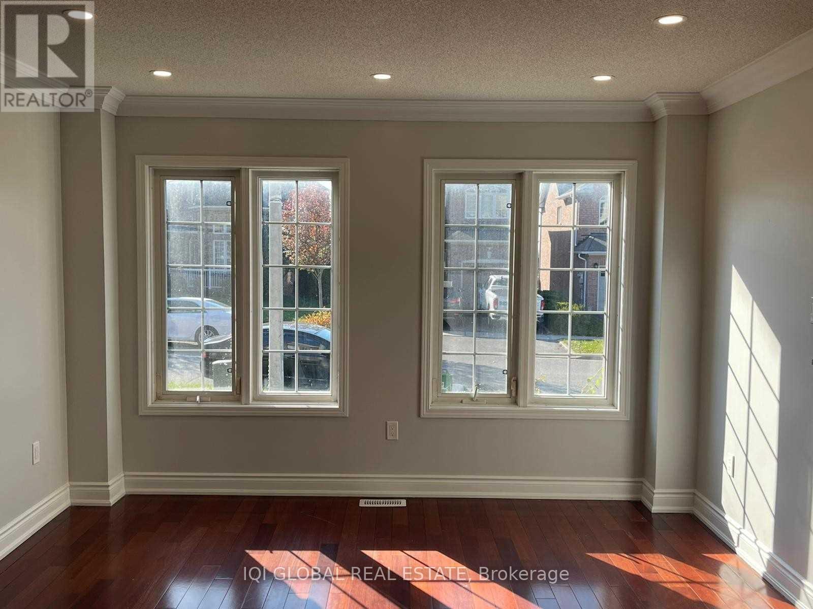A room with two windows and wooden floors.