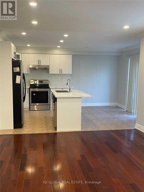 A kitchen with white cabinets and a black refrigerator.