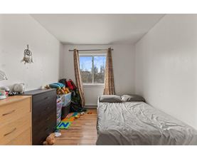 A bedroom with a bed, dresser, and window with curtains.