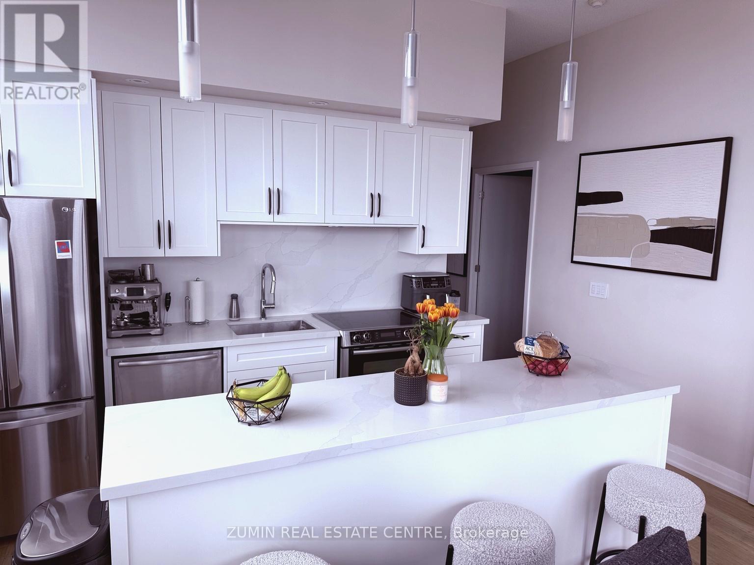 A kitchen with white cabinets and a white island with a bowl of bananas on it.