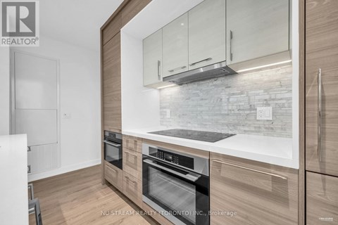 A modern kitchen with wooden cabinets and a stone backsplash.
